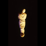 body wrapped in white cloth suspended in the air against a  black background